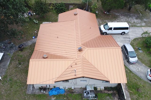 An aerial view of a house with a copper roof and a white van parked in front of it.