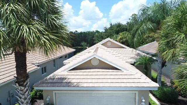 An aerial view of a house with a roof and palm trees.