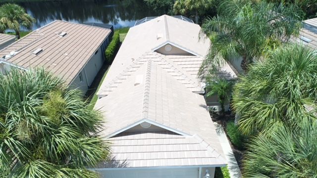 An aerial view of a house with a roof that is surrounded by palm trees.