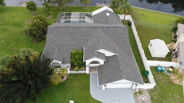 An aerial view of a house with a large roof and a pool.