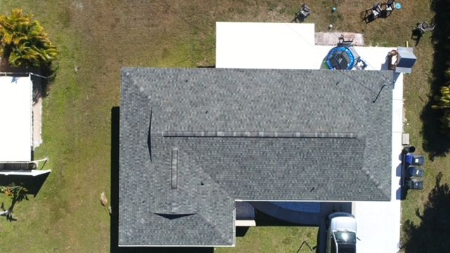 An aerial view of a house with a roof and a pool.