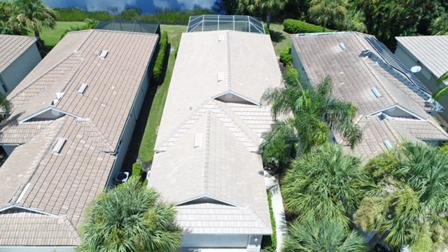 An aerial view of a row of houses with tile roofs surrounded by palm trees.