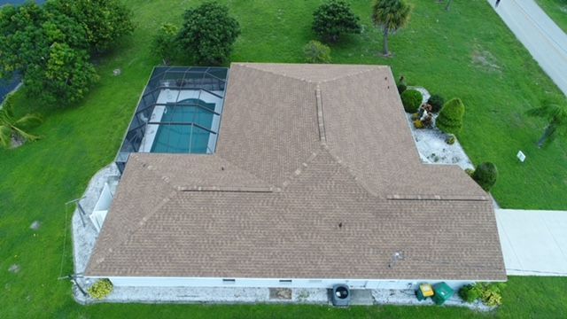 An aerial view of a house with a pool and a roof.