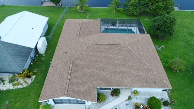 An aerial view of a house with a brown roof and a pool.