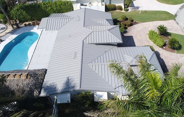 An aerial view of a house with a gray roof and a pool.