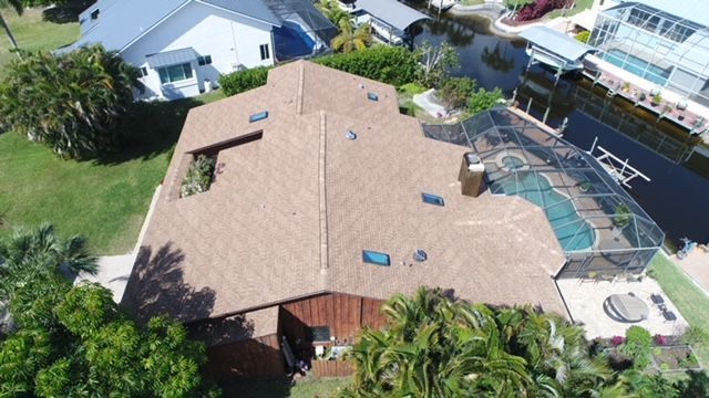 An aerial view of a house with a pool and a boat in the background.