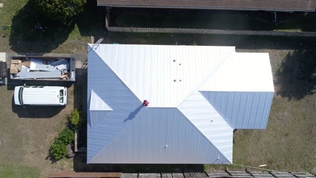 An aerial view of a house with a white roof.