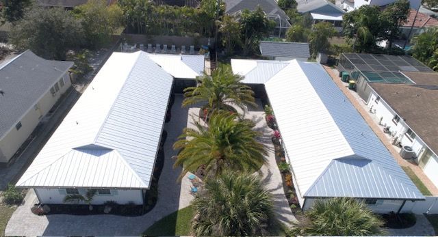 An aerial view of a row of houses with white roofs and palm trees