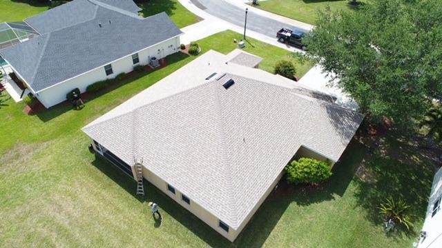 An aerial view of a house with a roof in a residential area.