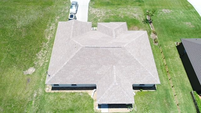 An aerial view of a house with a roof and a driveway.