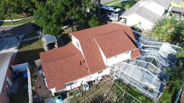 An aerial view of a house with a red roof in a residential area.