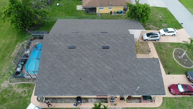 An aerial view of a house with a pool and cars parked in front of it.