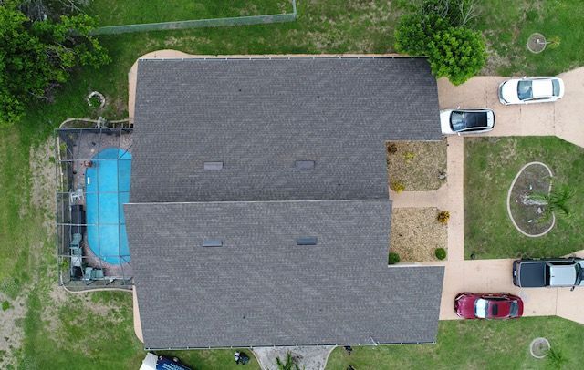 An aerial view of a house with a pool and cars parked in front of it.