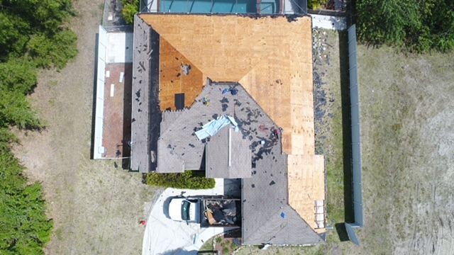 An aerial view of a house with a roof that is being repaired.