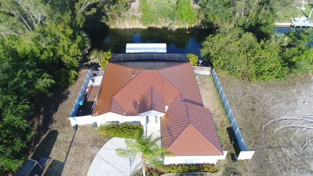 An aerial view of a house with a red roof surrounded by trees.