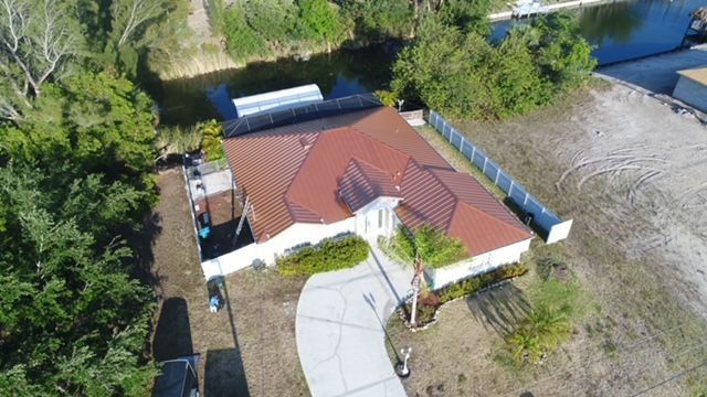 An aerial view of a house with a red roof next to a river.