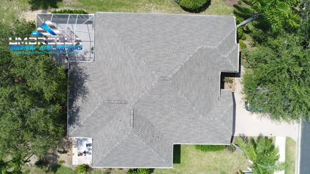 An aerial view of a house with a gray roof surrounded by trees.