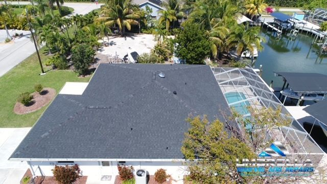 An aerial view of a house with a black roof and a pool.