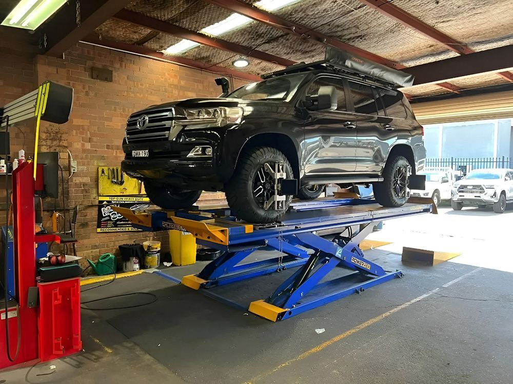 Black SUV on A Blue Scissor Lift in A Garage — AutoHop Lambton in Lambton, NSW