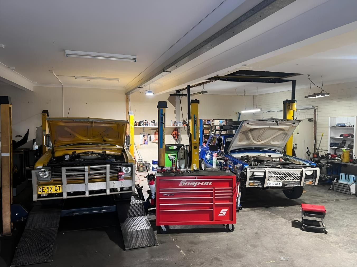 Two Cars on Lifts in A Garage with Tools and A Red Toolbox — AutoHop Lambton in Lambton, NSW