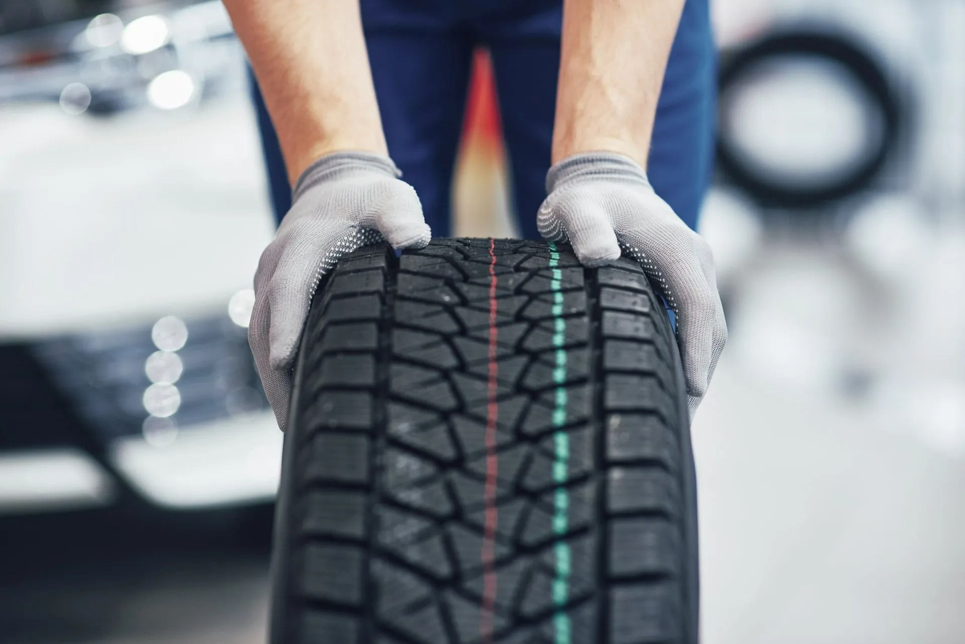 Person in Gloves Holding a Tire with Green and Red Stripes — AutoHop Lambton in Lambton, NSW