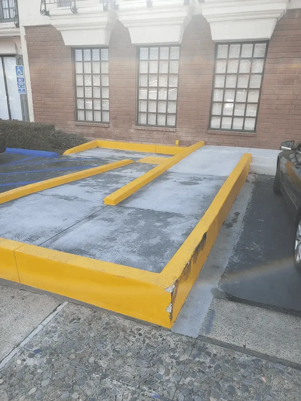 A car is parked in front of a building with a ramp.