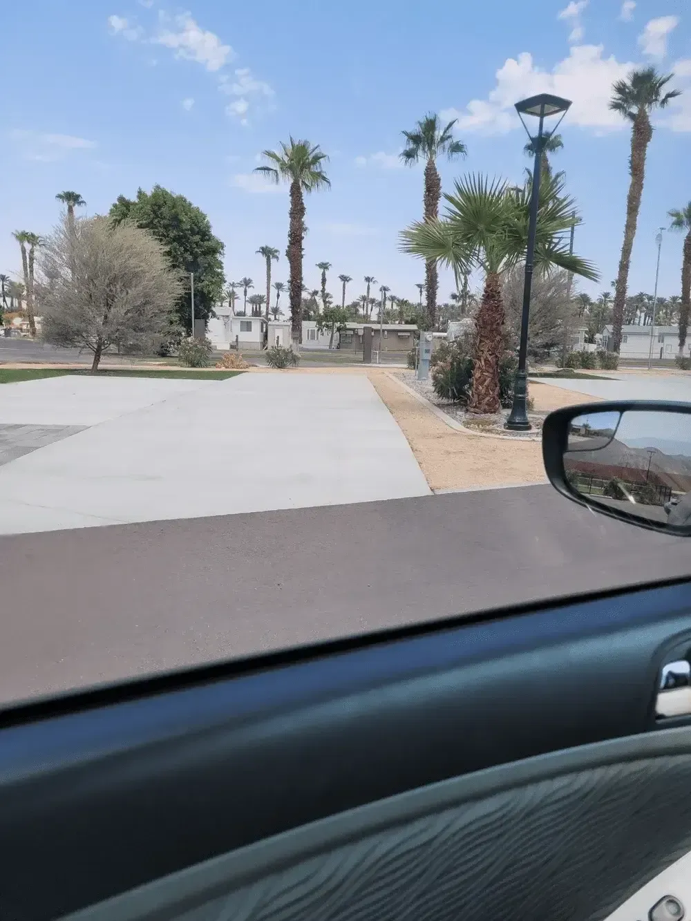 A car is driving down a road with palm trees in the background