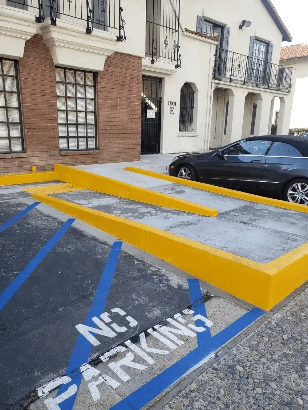 A no parking sign is painted on the side of a parking lot