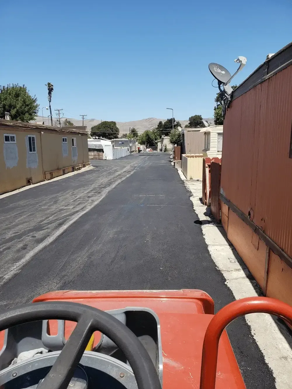 A red tractor is driving down a road in a residential area