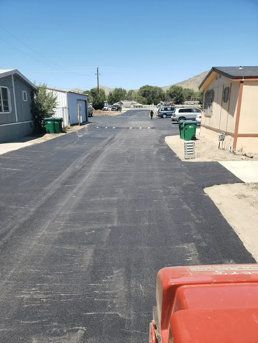 A red truck is parked on the side of a road in a mobile home park.