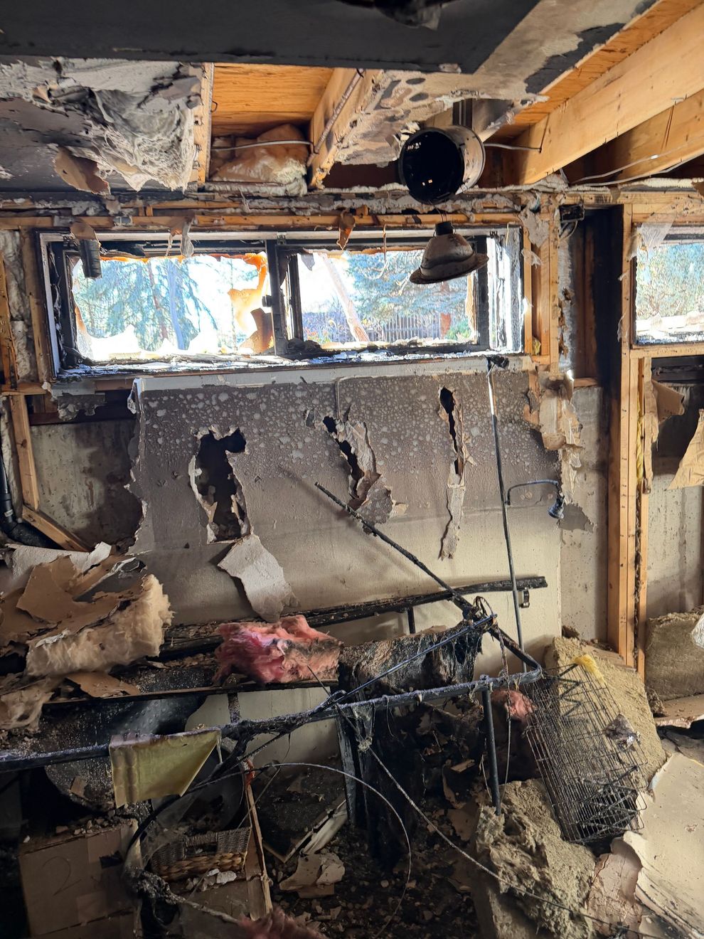 Interior view of a fire-damaged room with charred walls, exposed beams, and broken windows.