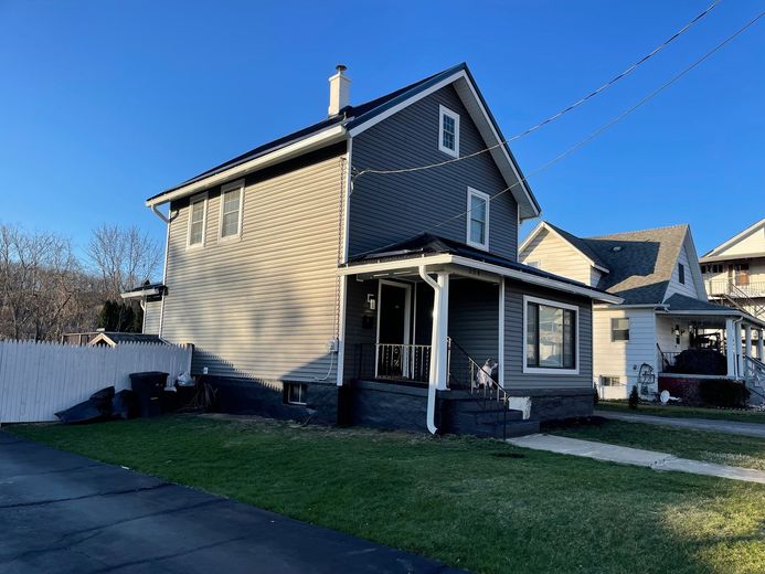 A house with a porch and a blue sky in the background.