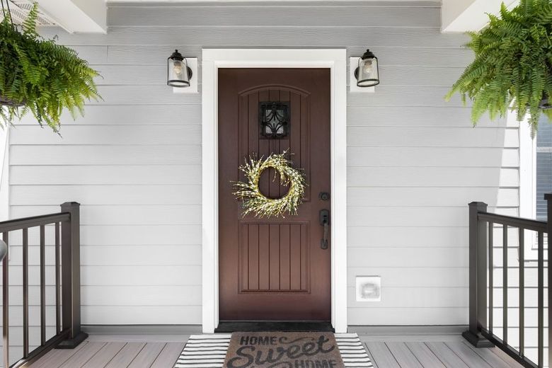 A brown front door with a wreath on it is on a porch.