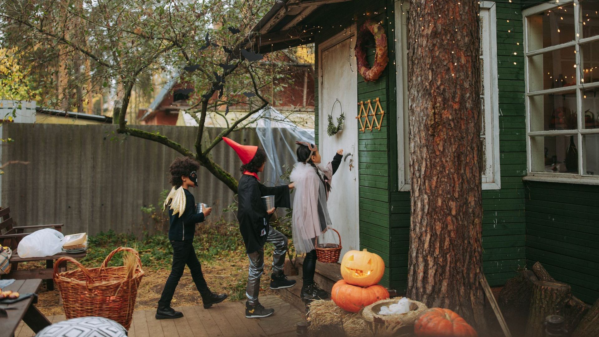 Three trick or treaters approach a door.