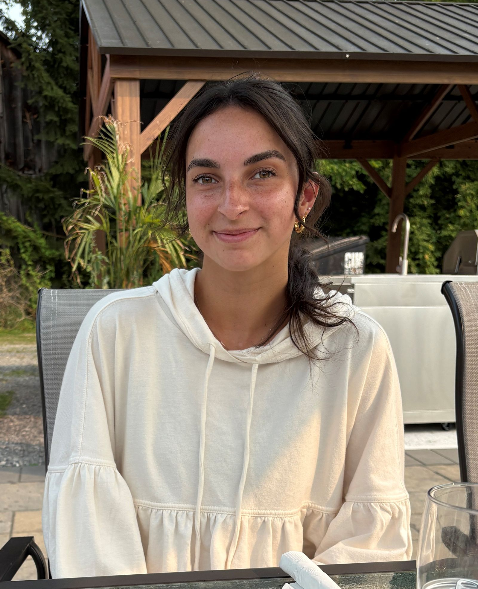 A woman wearing glasses and a grey shirt is smiling for the camera.