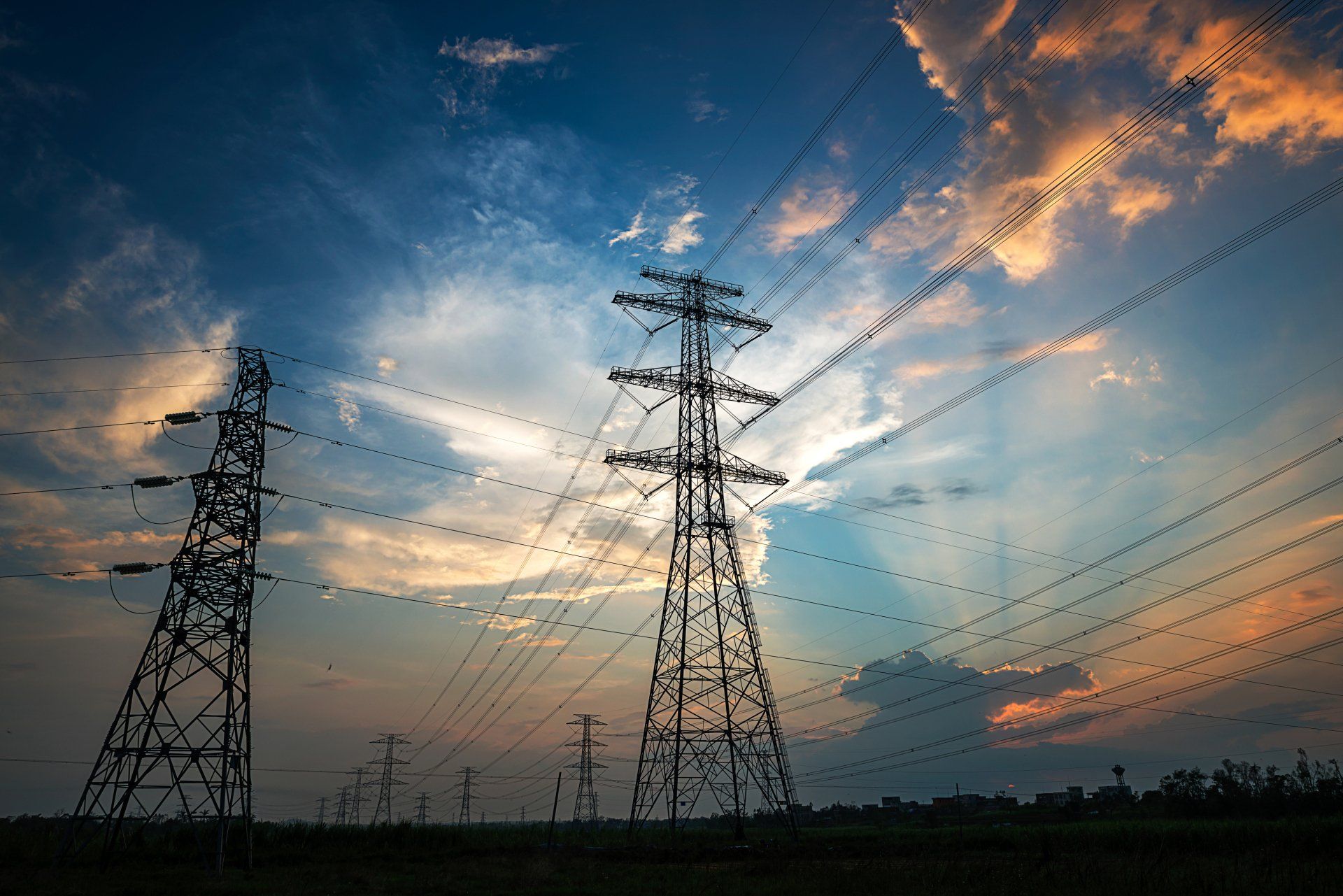 a row of power lines against a cloudy sky at sunset
