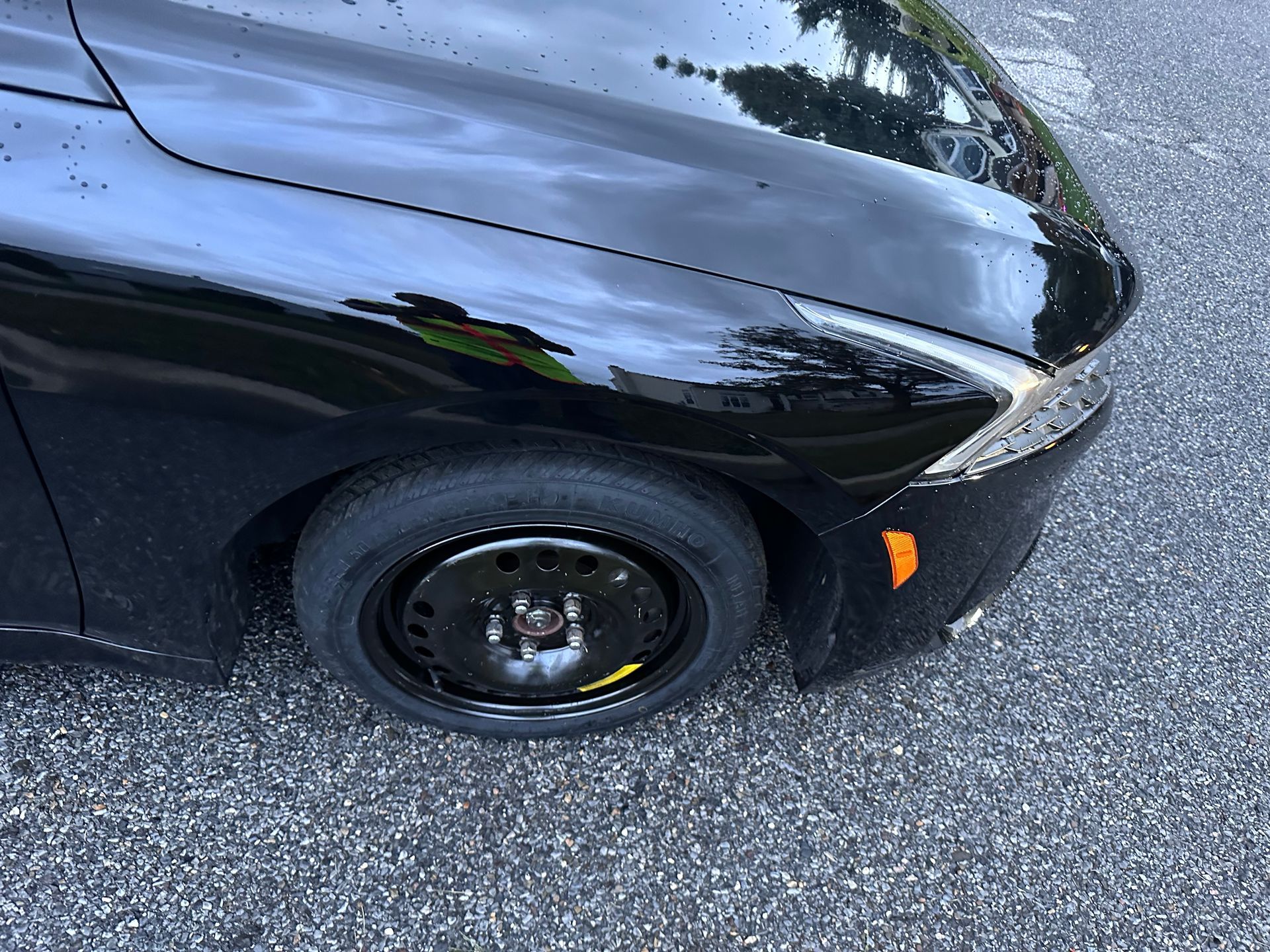 A roadside assistance technician in a high-visibility vest tightens lug nuts on a car 