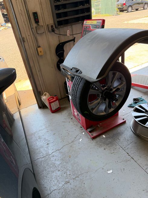 Large tire mounted on a red machine in a workshop, with a gray fender covering part of it.