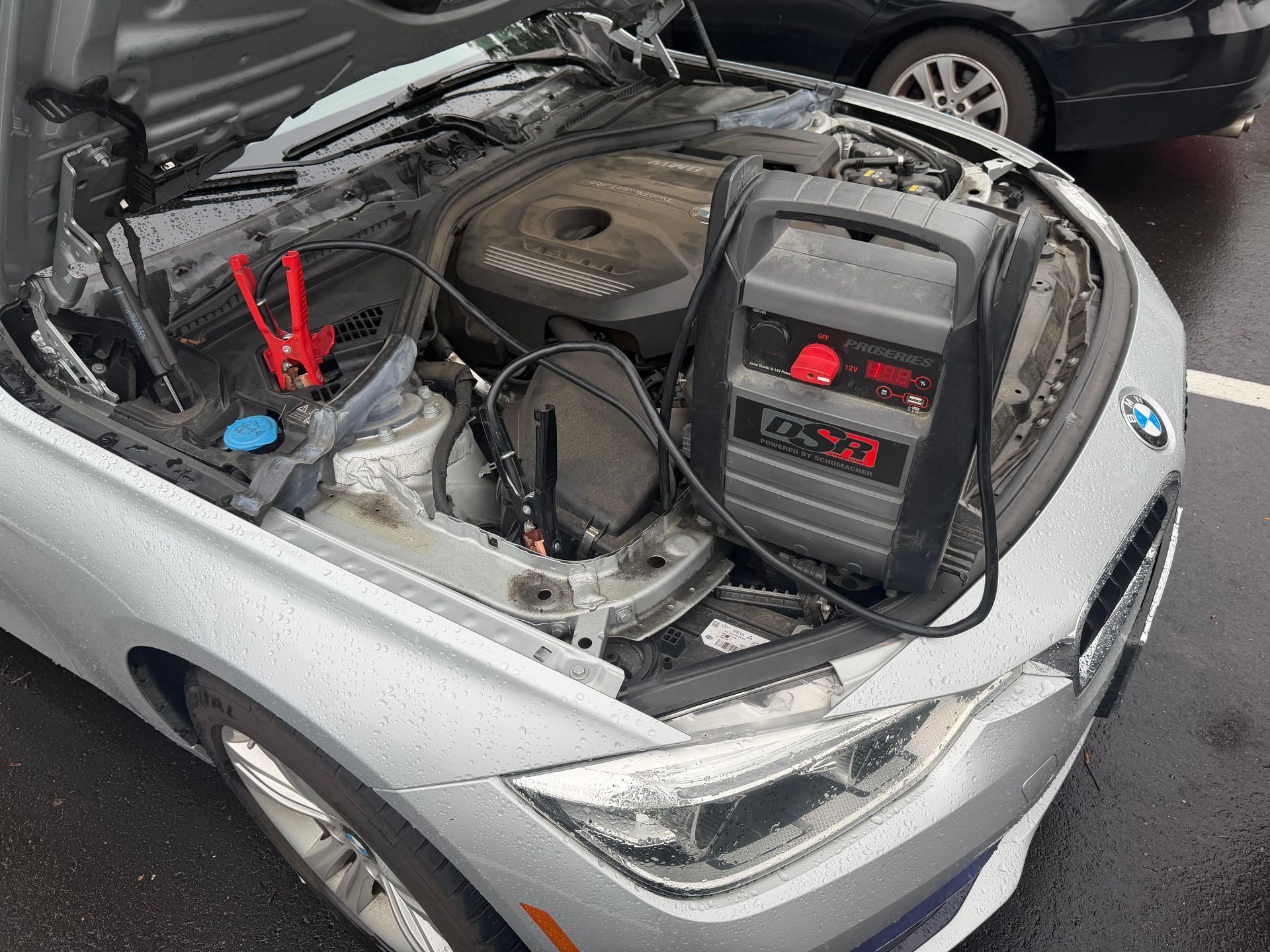 Red and black jumper cables connected to a black car battery.