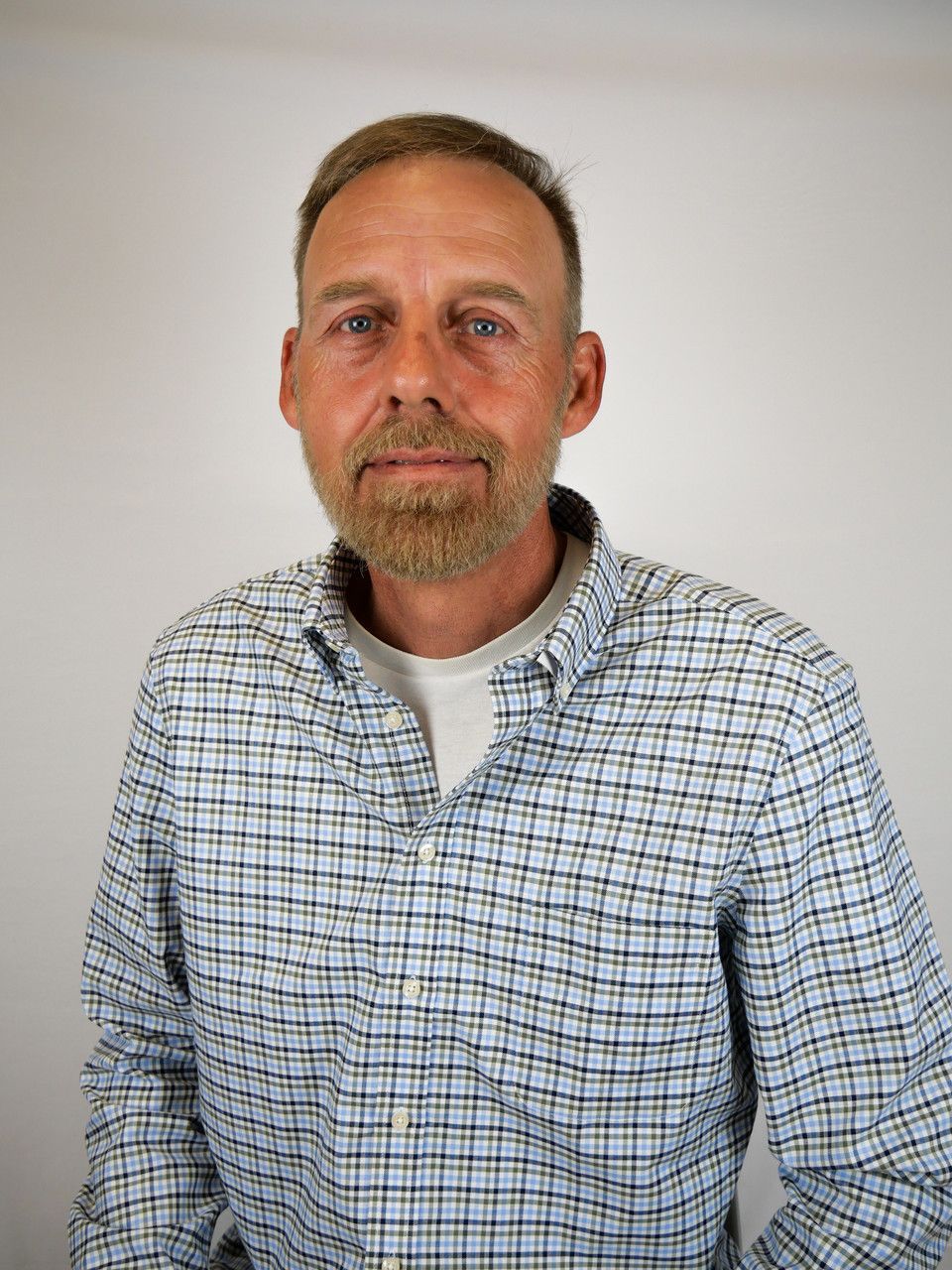 A man with a beard is wearing a plaid shirt.