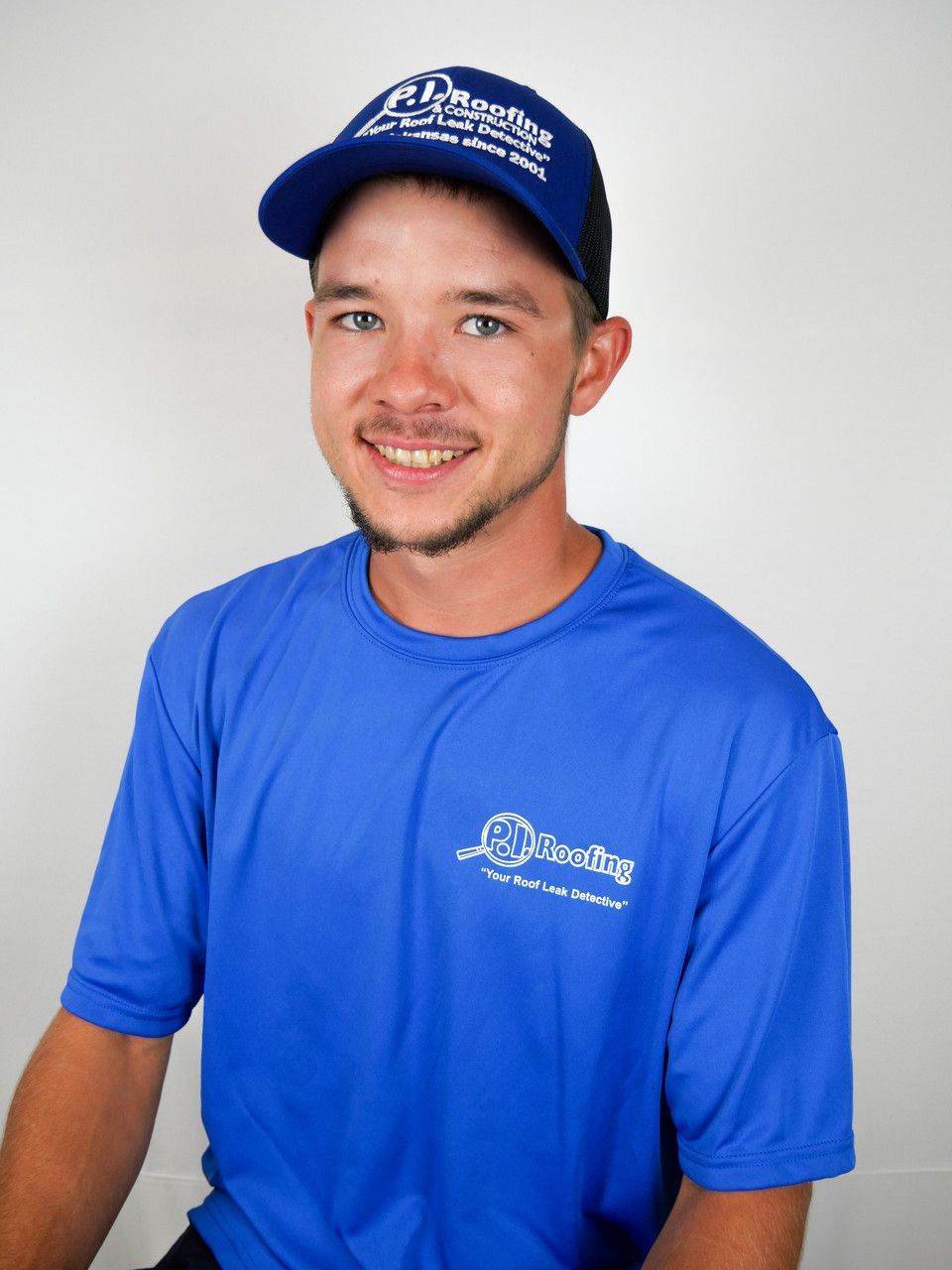 A man wearing a blue shirt and a hat is smiling