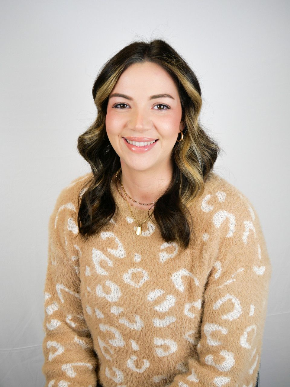 A woman in a yellow and white sweater is smiling for the camera.
