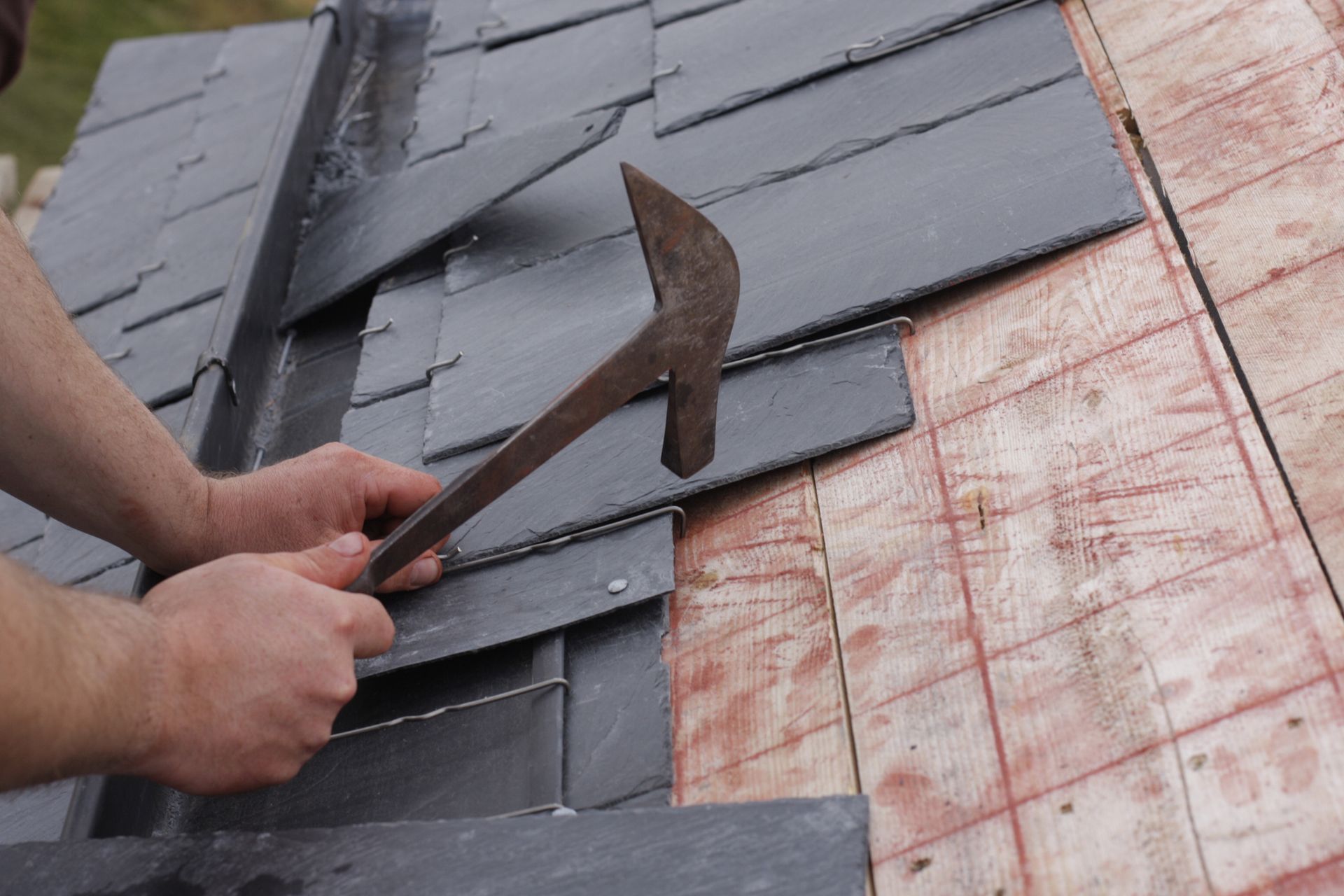 A man is working on a roof with a hammer and chisel.
