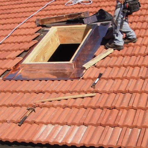 A close up of a red tile roof with an opening