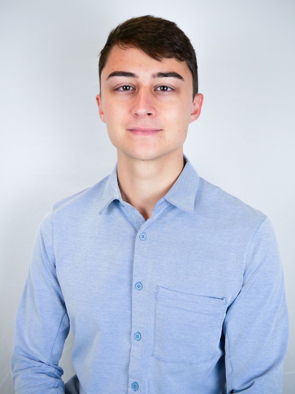 A young man wearing a light blue button down shirt
