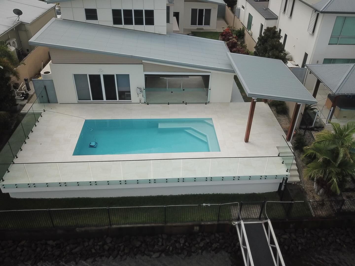 Modern house with pool and a dock. The pool is turquoise, and the roof is silver.