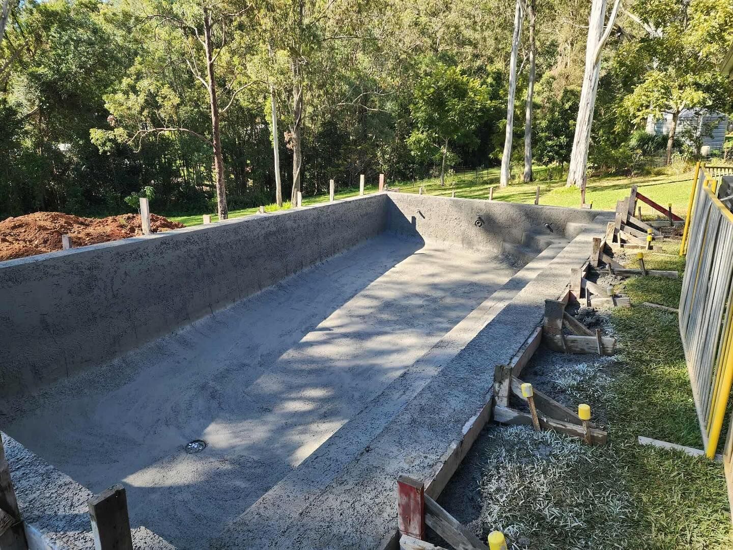 Concrete swimming pool under construction outdoors.