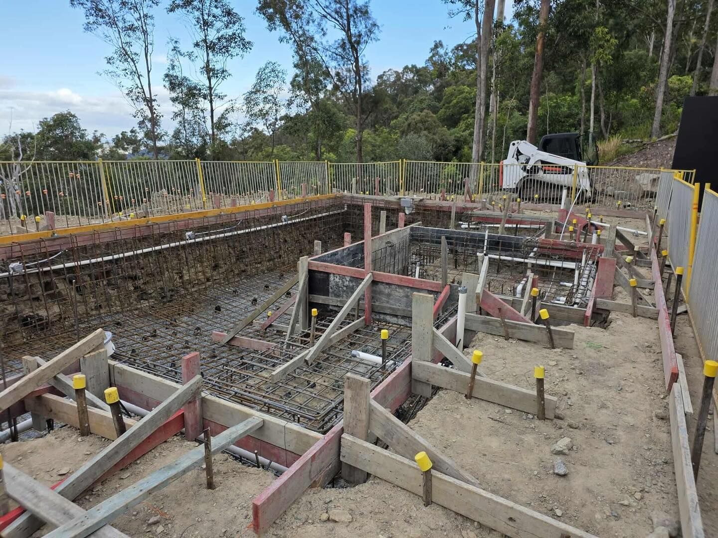 Construction site with wooden framework and rebar, in an outdoor setting.