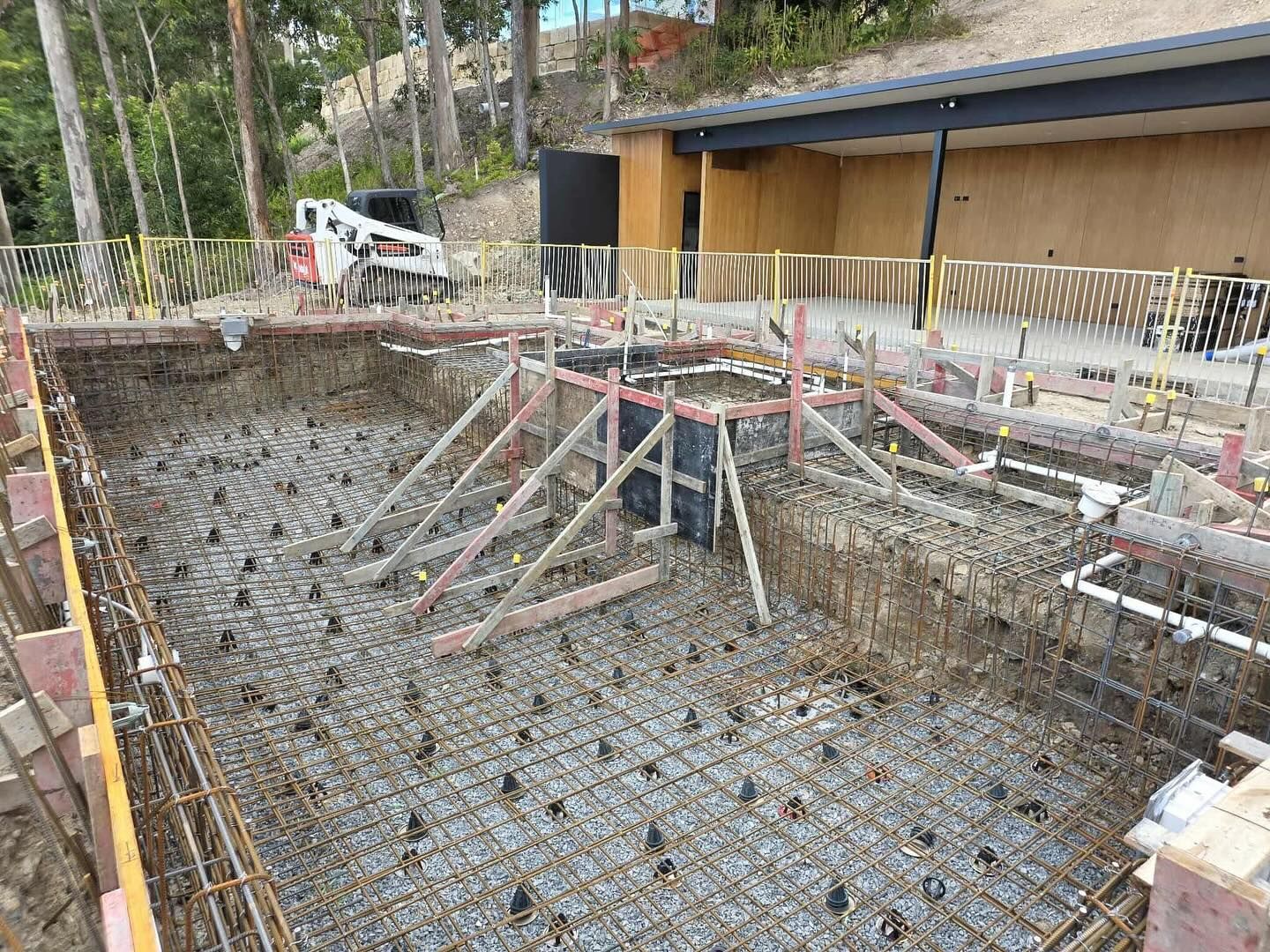 Construction of a rectangular concrete pool with exposed rebar and wooden support structures.