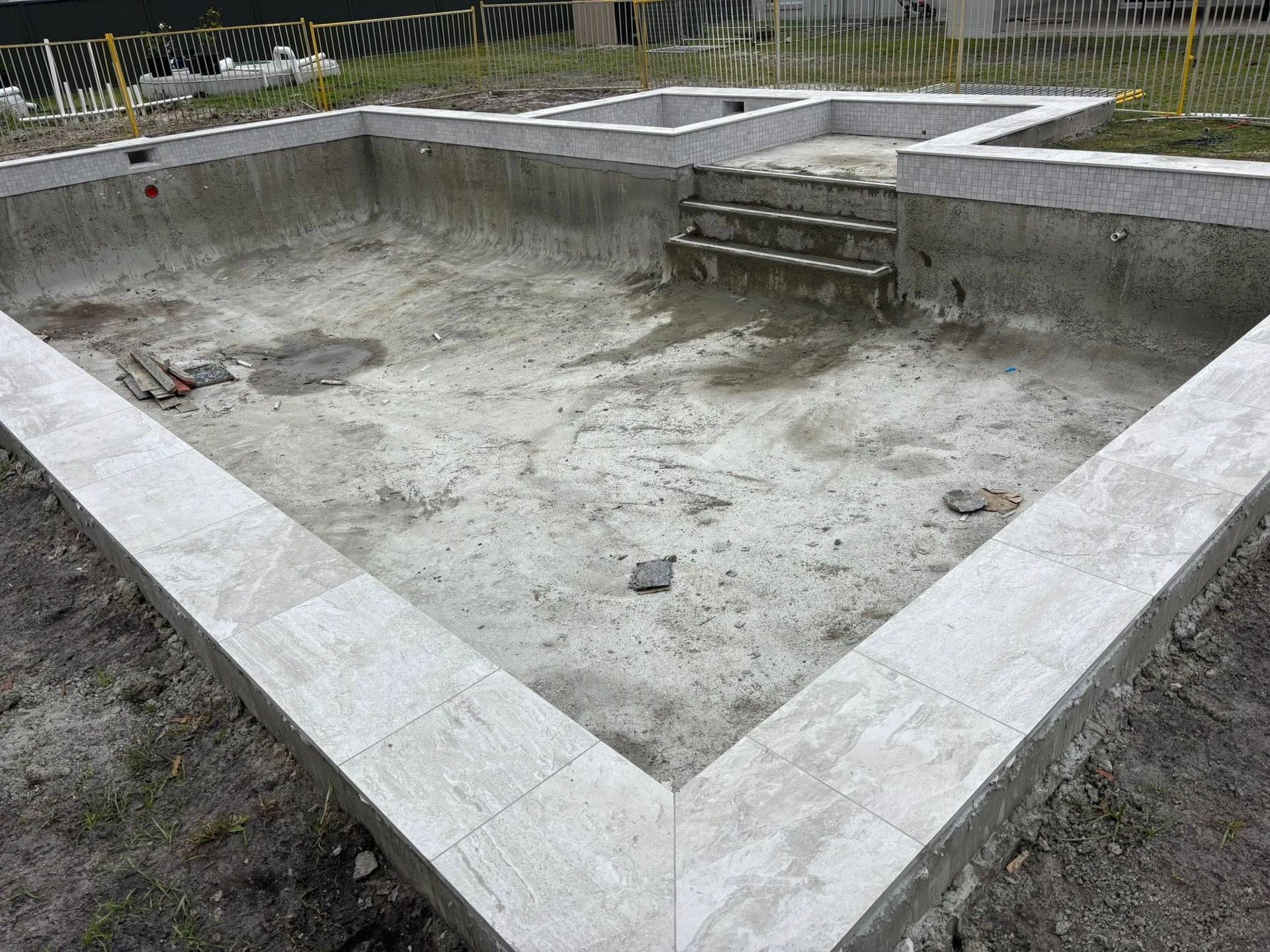 Empty concrete swimming pool under construction, with steps.